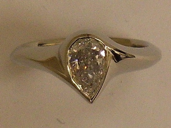 Solitaire Engagement Ring With Pear Shaped Diamond in Center of White Gold Mounting Bezel Set